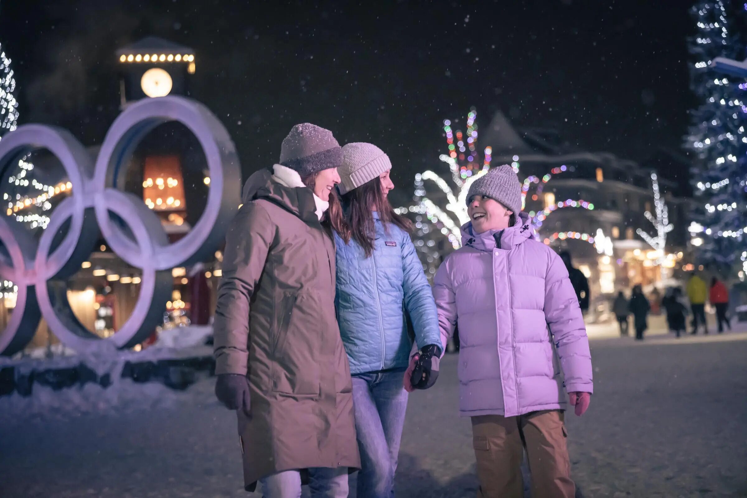 Family walking past the Olympic rings in Whistler Village at night